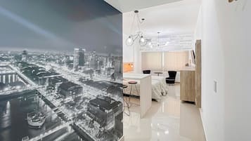 Habitación de hotel moderna con vistas a un paisaje urbano, una cama, un escritorio y una silla.
