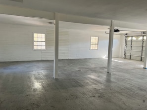 A spacious interior with white walls, concrete flooring, and two windows.