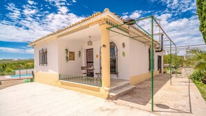 Una casa de un piso con techo de tejas, balcón y piscina.