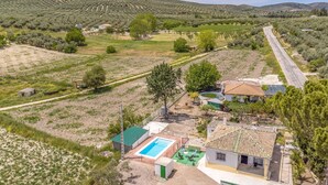 Un barrio residencial con piscina, una casa de techo a tejas y una carretera que serpentea por el paisaje.