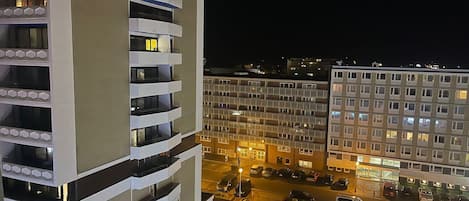 A multi-story hotel with balconies, a parking lot, and a street view at night.