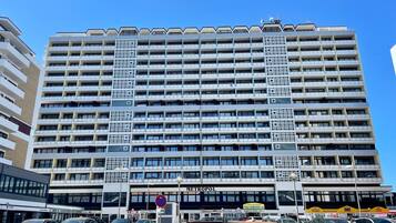 A multi-story hotel with a modern architectural design, featuring a prominent entrance and a parking area in front.