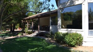 Una casa moderna con un portico coperto, ampie finestre e un prato curato.
