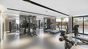 Et moderne fitnesscenter med forskellig træningsudstyr, store vinduer og en ren, rummelig indretning.