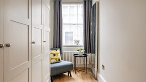 Une pièce d’angle avec un canapé gris, une petite table sur laquelle est posée une plante, et un radiateur.