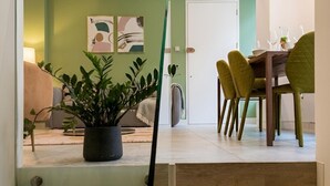 Un interior moderno con una escalera que conduce a un comedor, un sofá y una planta en maceta.