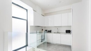 Una cocina moderna con gabinetes blancos, un salpicadero de vidrio y un horno empotrado.