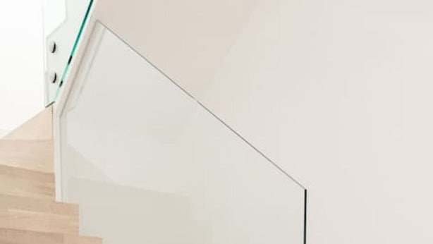 Una escalera con escalones de madera y barandilla de cristal.
