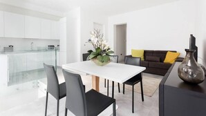 Un espacio moderno de estar con comedor, cocina y un sofá con cojines.