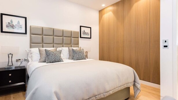Une chambre moderne avec un grand lit, une armoire en bois et deux tableaux encadrés accrochés au mur.