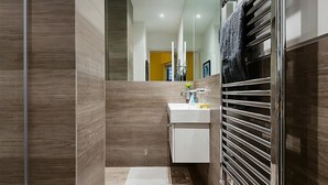 Un baño moderno con lavamanos, espejo y barra para toallas blancos.