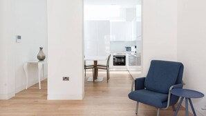 A modern kitchen with white cabinets, a dining table, and a blue chair.