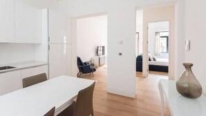 A modern apartment with a kitchen, dining area, and a living room with a sofa and a TV.