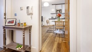 A modern kitchen with white cabinets, a microwave, and a dining area with a table and chairs. - Lovely 1 Bedroom at the British Museum (Greater London)