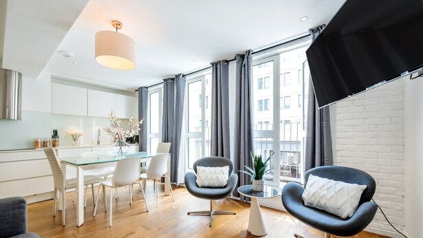 A modern living room with a glass dining table, two armchairs, and a small side table. - Splendid 2 Bedroom in Covent Garden (Greater London)
