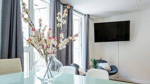 A modern living room with a glass table, a vase of flowers, a flat-screen TV, and a sofa. - Splendid 2 Bedroom in Covent Garden (Greater London)