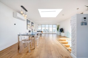 Ein moderner Wohnbereich mit Essplatz, einer Treppe und einem großen Fenster, das für natürliches Licht sorgt.