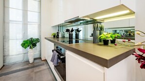 Una cocina moderna con un amplio ventanal, horno empotrado y diversas plantas en macetas.