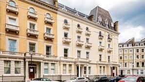 Ein mehrstöckiges Gebäude im klassischen Stil, mit einer symmetrischen Fassade und gleichmäßig angeordneten Fenstern und Balkonen.