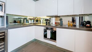 Eine moderne Küche mit weißen Schränken, Edelstahlgeräten und einer zentralen Kochinsel mit integriertem Backofen.