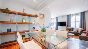 Ein modernes Wohnzimmer mit einem Glastisch, einer Couch und einem an der Wand befestigten Fernseher.