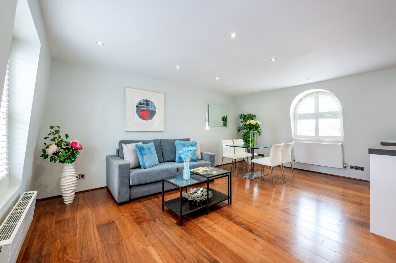 Un salon moderne avec un canapé gris, une table basse et un coin repas comprenant une table et des chaises blanches.
