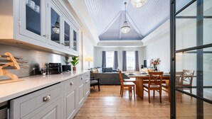 A modern kitchen with white cabinets, a wooden countertop, and a dining area with a table and chairs. - Unique Covent Garden Townhouse! (Greater London)