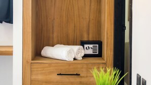 Un armario de madera con calefacción integrada, una mesita de noche pequeña con una planta y un calefactor de pared.