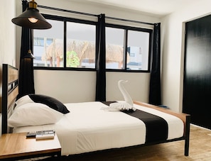 A modern hotel room with a large bed, a bedside table, a lamp, and a view of the outside. - Casa Maca (Playa del Carmen)