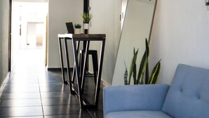 Un interior moderno con un sofá azul, una mesa de comedor con sillas y plantas en macetas.