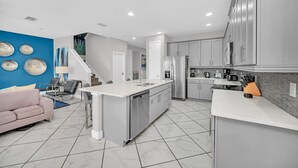 A modern kitchen with white countertops, stainless steel appliances, and a grey backsplash. - 8BR Spectacular Villa • Games Room • Near Disney (Kissimmee)