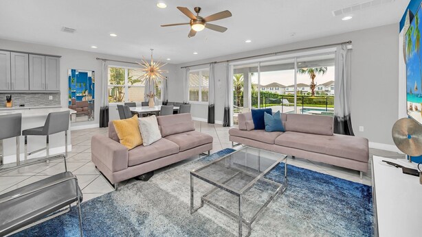 A spacious living area with a sofa, coffee table, and a dining table with chairs. - 8BR Spectacular Villa • Games Room • Near Disney (Kissimmee)
