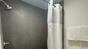 Une salle de bain avec une douche, des toilettes et un porte-serviettes.