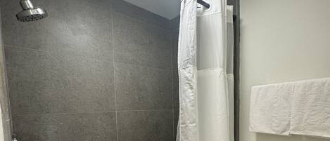 Un baño con ducha, inodoro y un perchero para toallas.