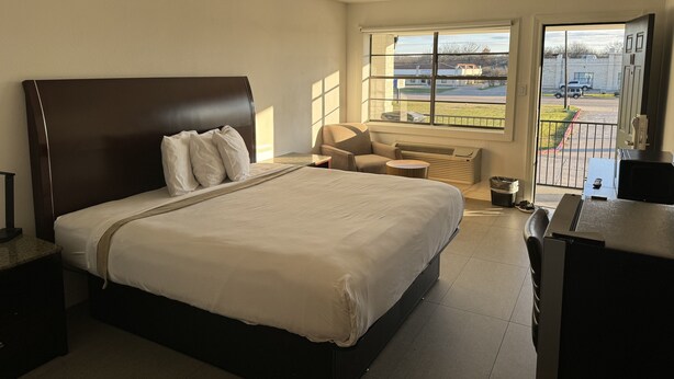 Une chambre d’hôtel avec un grand lit, un bureau, une chaise et une fenêtre donnant sur l’extérieur.