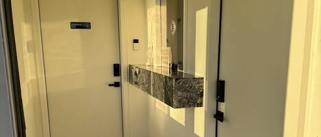 Un couloir avec une porte portant l’inscription « Réservé au personnel », un sol carrelé et un miroir fixé au mur.