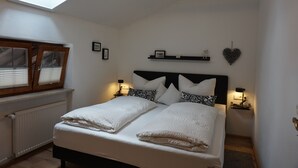 A bedroom with a skylight, a bed with white linens, a black headboard, and bedside lamps. - Drei-raum-ferienwohnung Winklmoos, 65qm, Dusche/wc, Extra Bad, Extra Schlafraum, Küche, Balkon (Reit im Winkl)