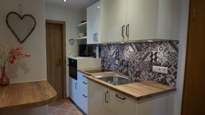 A compact kitchen with white cabinets, a wooden countertop, and a patterned backsplash. - Drei-raum-ferienwohnung Winklmoos, 65qm, Dusche/wc, Extra Bad, Extra Schlafraum, Küche, Balkon (Reit im Winkl)