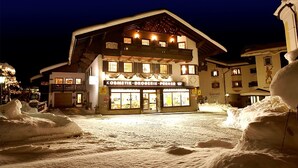 A hotel with a sign reading "KOSMETIK-DROGERIE-PÖNER" at night, surrounded by snow. - Drei-raum-ferienwohnung Winklmoos, 65qm, Dusche/wc, Extra Bad, Extra Schlafraum, Küche, Balkon (Reit im Winkl)