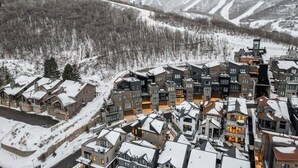 A snow-covered residential area with modern houses, a ski lift, and a mountain backdrop. - Luxe Park City Ski-In/Ski-Out Retreat (Park City)