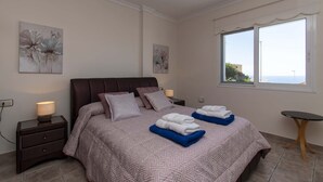 Un dormitorio con cama, mesitas de noche, una mesa y obras de arte en las paredes.