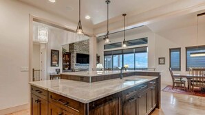 A spacious kitchen with a large island, wooden cabinets, and pendant lighting. - Highland Heights! Luxe Mountain VIEWS w/ Hot Tub (Colorado Springs)