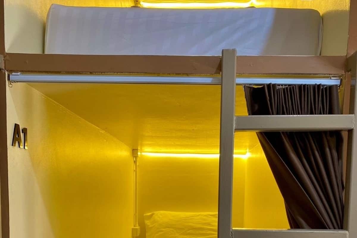 A bunk bed with a ladder, a headboard, and a curtain.