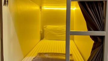 Una cama individual con escalera, cabecera y cortina.