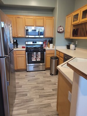 A kitchen with wooden cabinets, stainless steel appliances, and a herringbone-patterned floor.