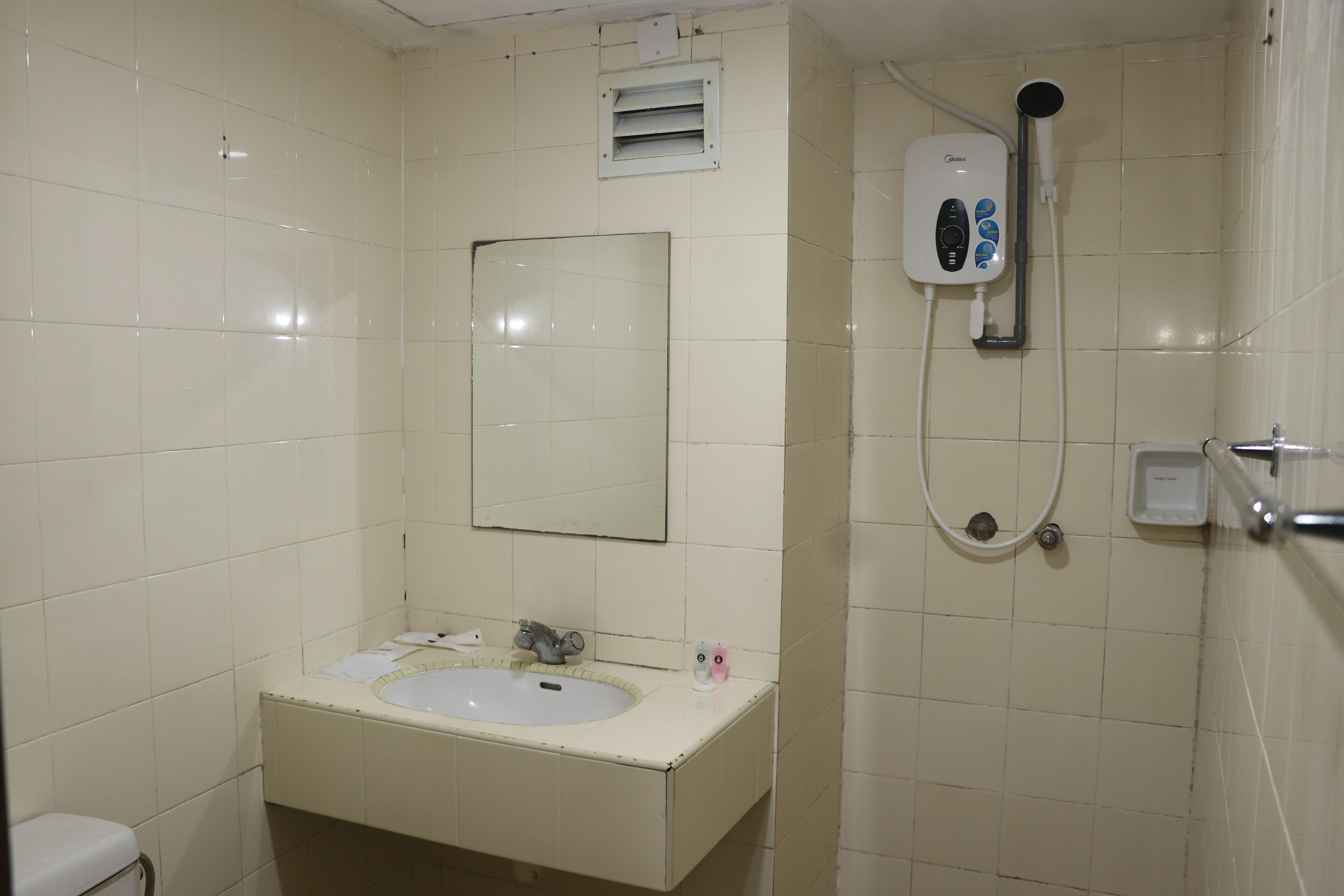 Ein Badezimmer mit Waschbecken, Spiegel, Dusche und Toilette.
