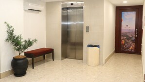 An elevator in a lobby with a potted plant and a bench. - Hotel Seri Putra  (Kuala Lumpur)