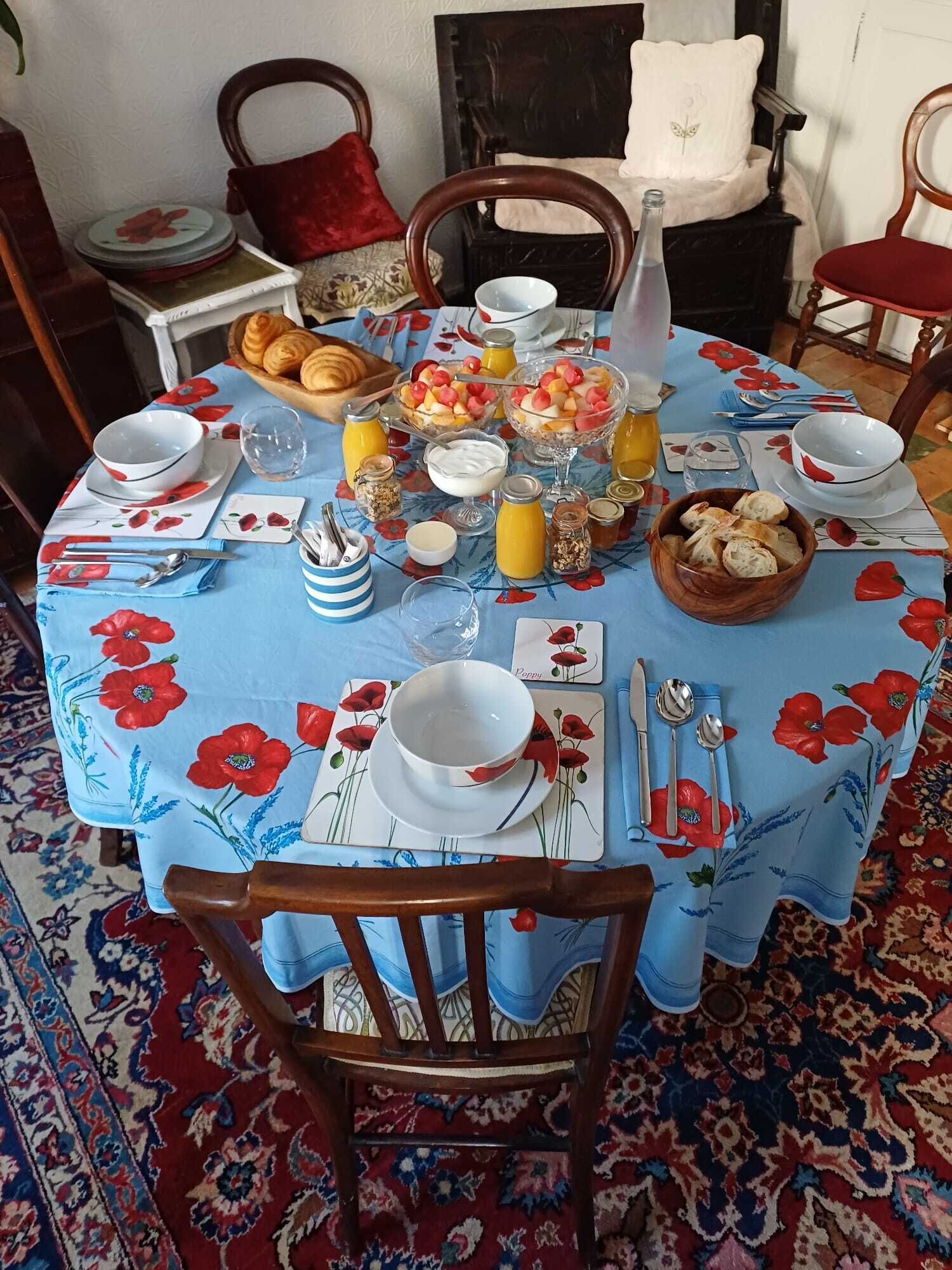A dining table set with a floral tablecloth, various dishes, and bread.