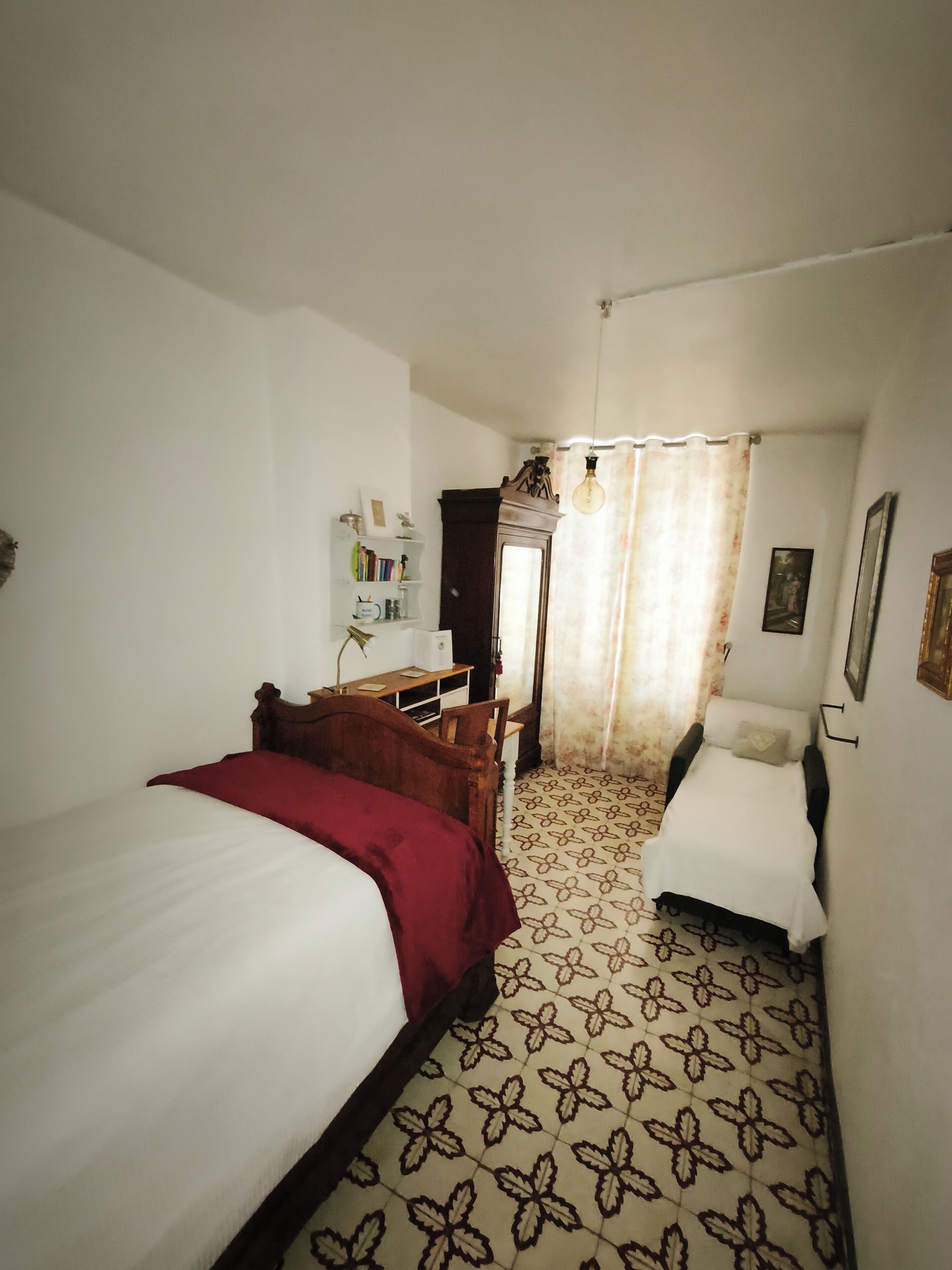Una camera da letto con due letti, una scrivania, una sedia, un armadio e un pavimento decorato.