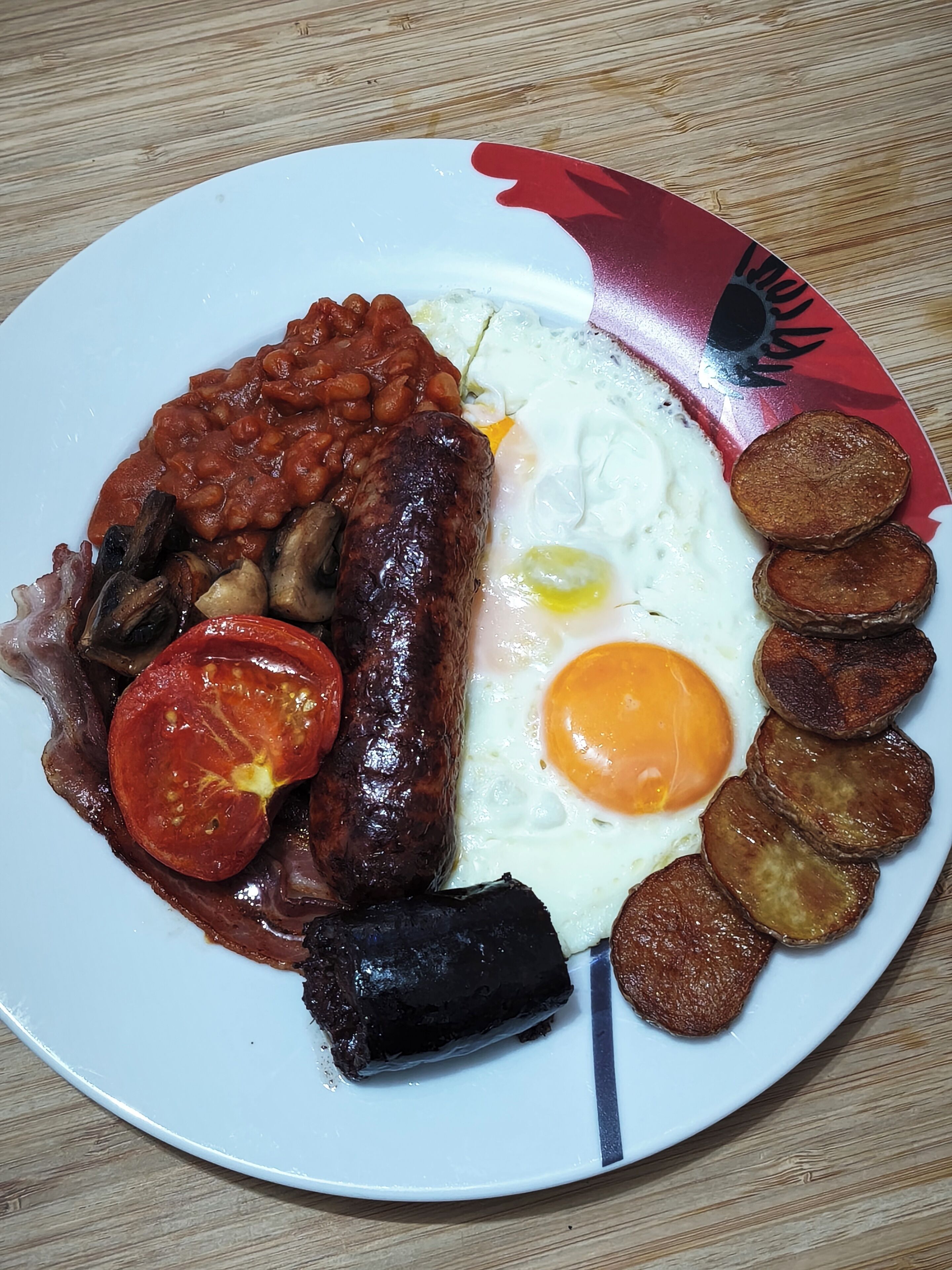 A plate of food with beans, sausage, egg, and fried potatoes.